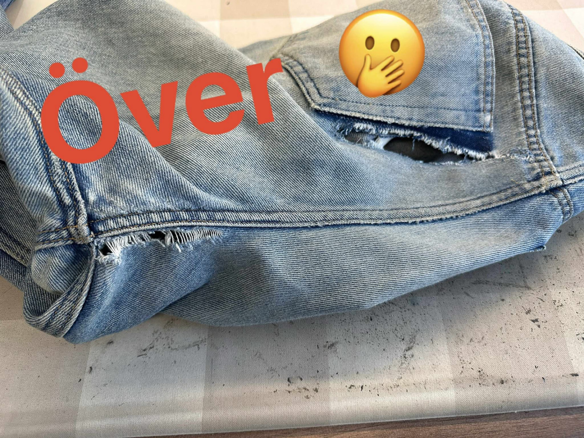 Ljusa jeans med hål vid bakfickan före lagning